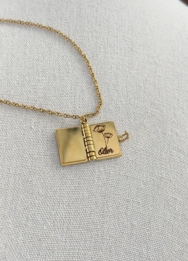 Personalized gold book necklace engraved with flowers and the name Oliver