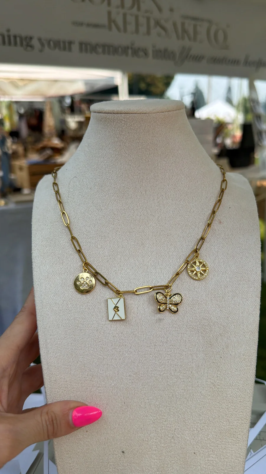 Gold charm necklace displayed at a Golden Keepsake Co. event