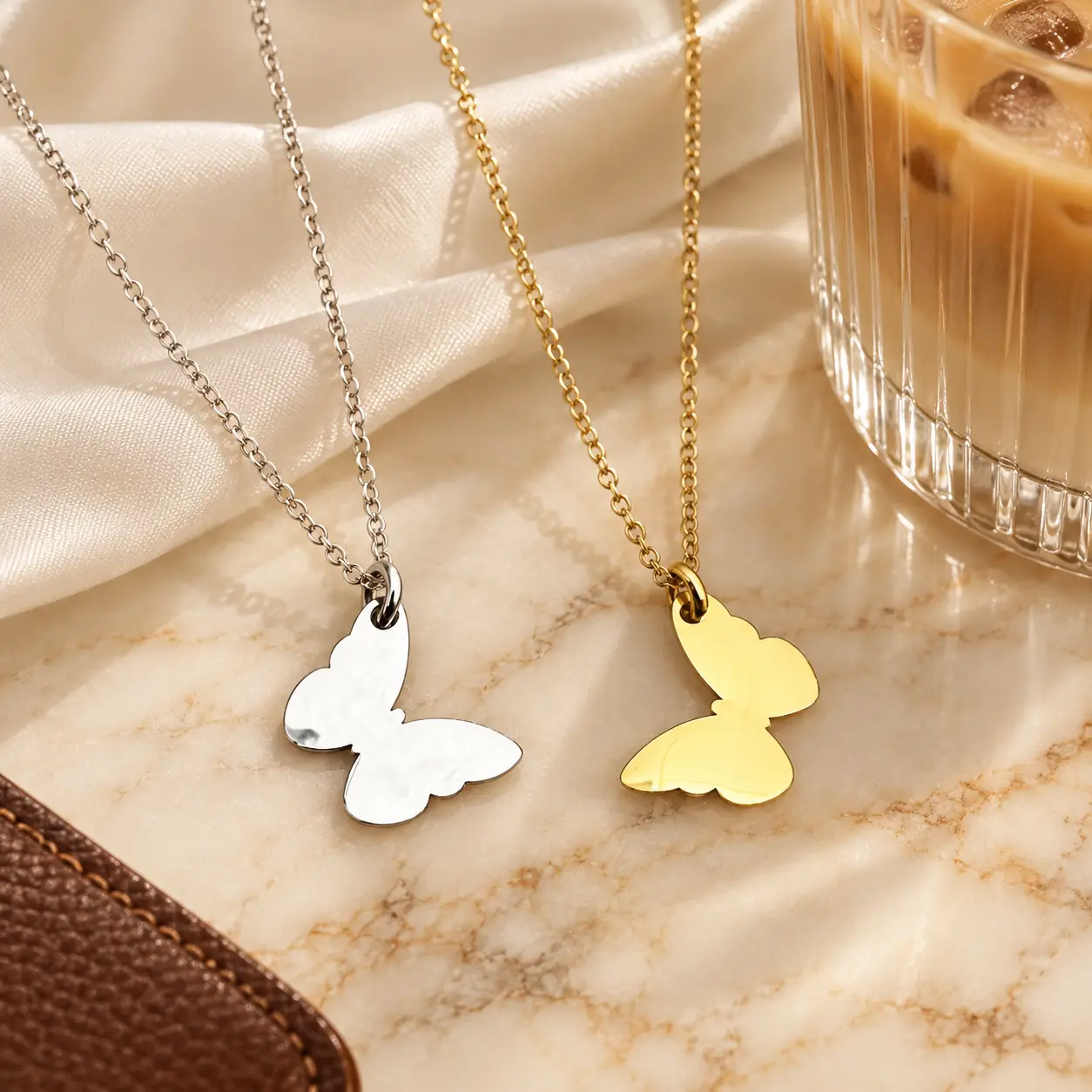 Gold and silver Butterfly Pendant Necklaces displayed on ivory satin and marble